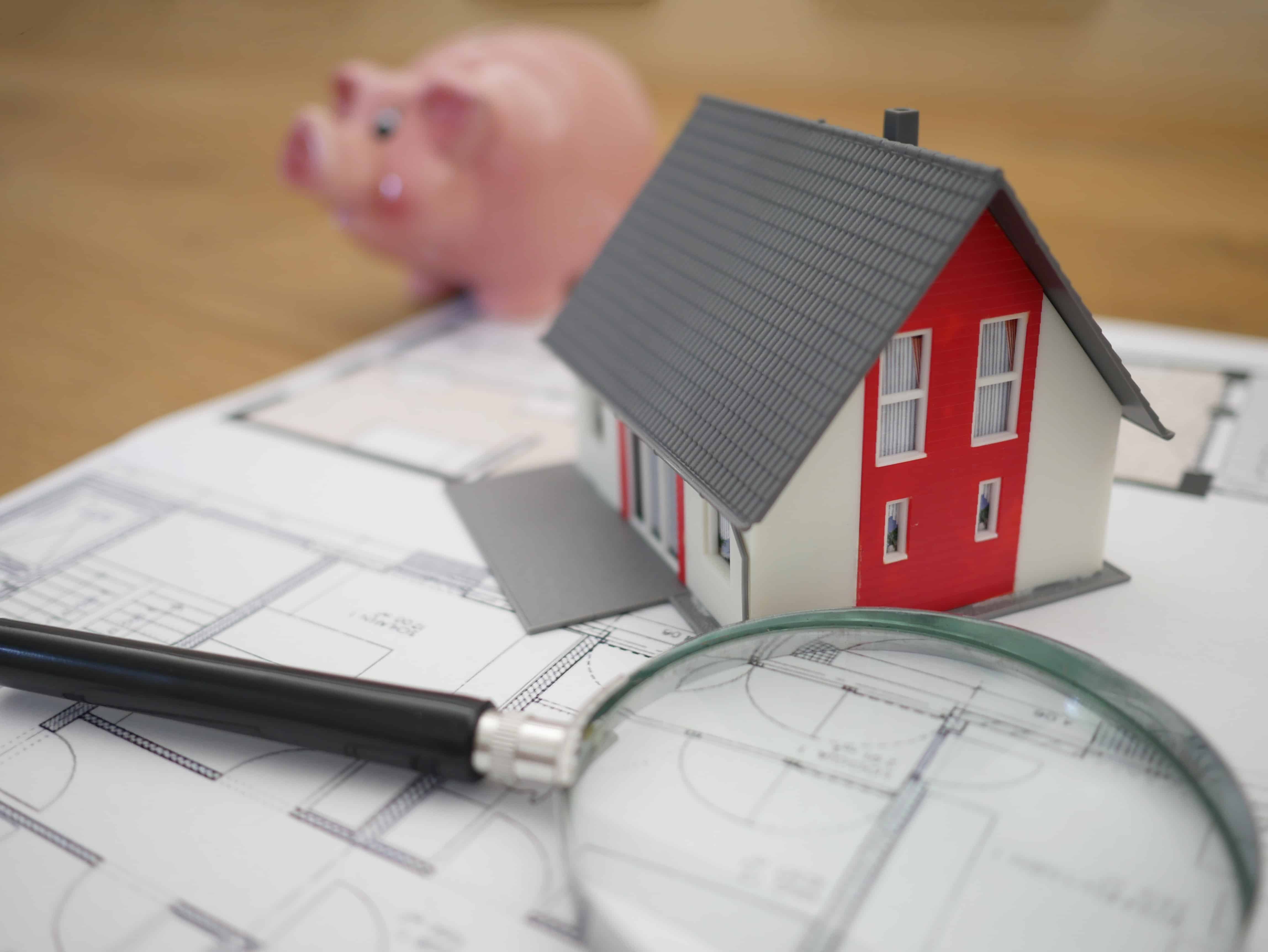 Small house on a table with plans and a piggy bak